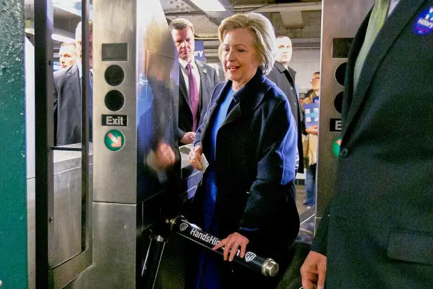 FILE - Democrat presidential candidate Hillary Clinton holds her MetroCard as she goes through the turnstile to enter the subway in the Bronx borough of New York, April 7, 2016. (AP Photo/Richard Drew, File)