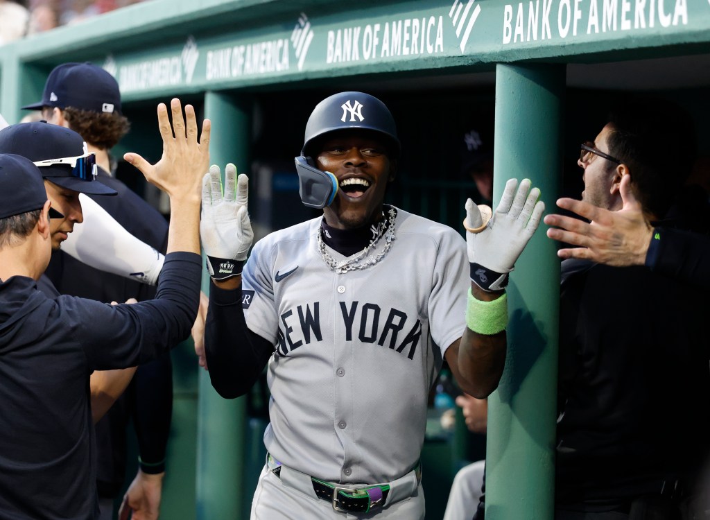 Jazz Chisholm Jr. #13 of the New York Yankees is greeted by his teammates in the dugout after he scores on his solo homer