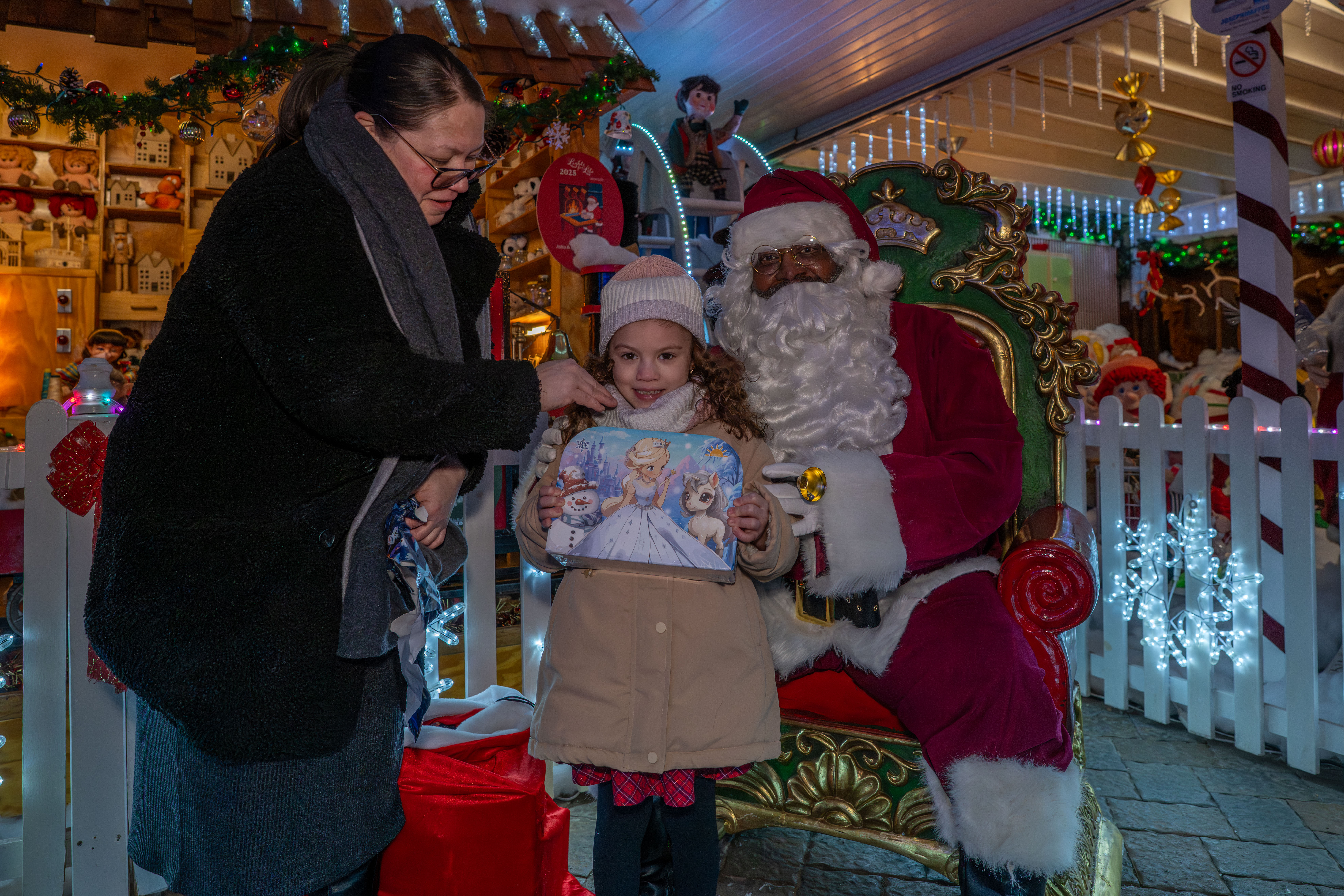Taisha Figueroa, a Northwell Staten Island University Hospital employee who is being honored with a Day of Surprises, with her granddaughter, Julissa Irrizarry, 6, and Santa Claus at the DeMartino Christmas House in Charleston on Tuesday, December 16, 2025. (Owen Reiter for the Advance/SILive.com)
