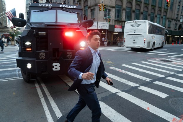 A fleeing office worker runs past an NYPD Bearcat as it arrives on the scene of an active shooter situation on Park Ave. in Midtown Manhattan on Monday, July 28, 2025. (Barry Williams/New York Daily News)