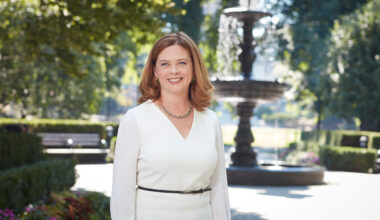 Fordham President Tania Tetlow in white dress in front of fountain