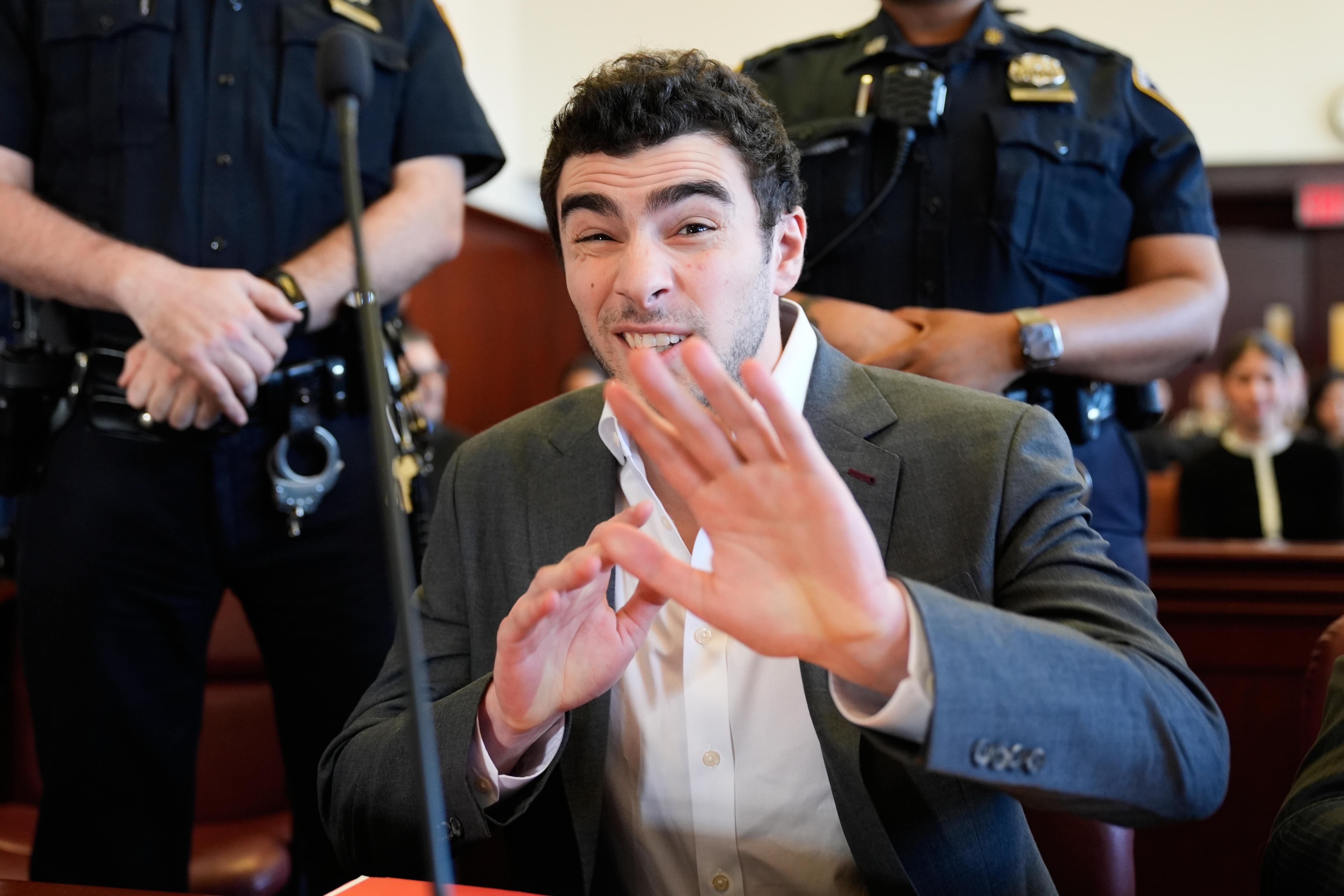 Luigi Mangione talks to a photographer as he appears in...