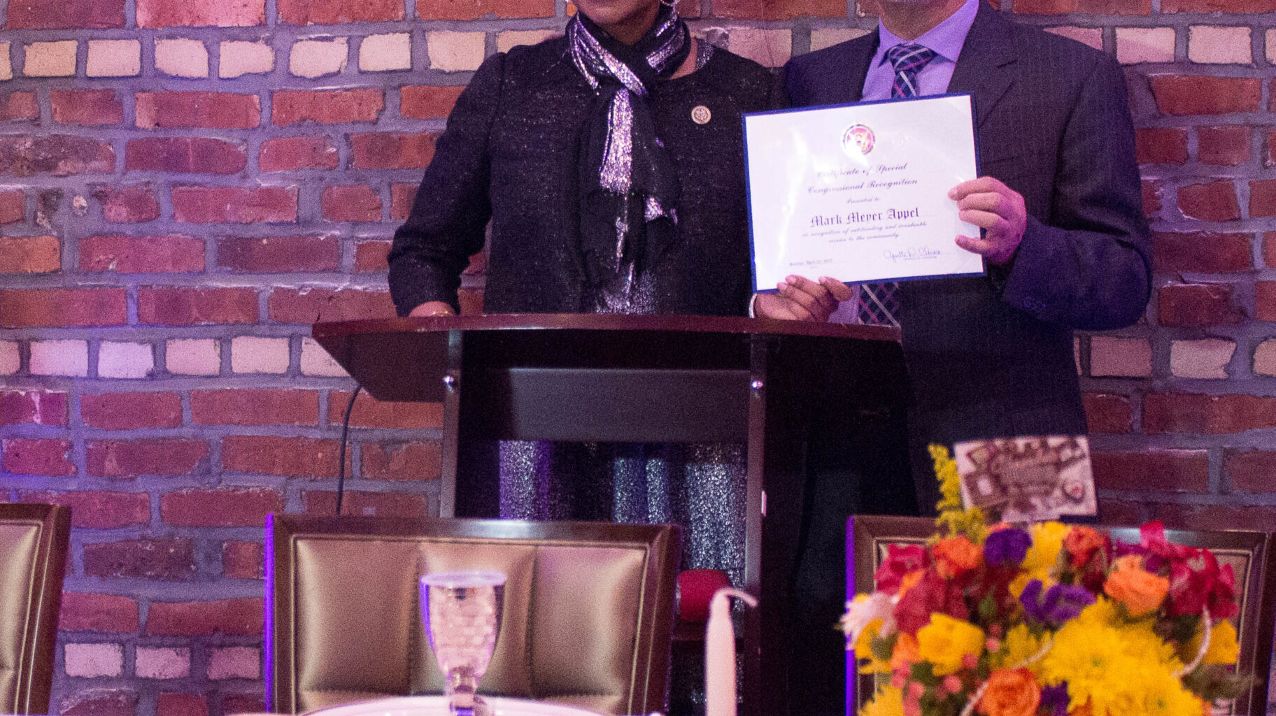 The Bridge Multicultural Project’s president Mark Appel, pictured receiving a recognition certificate from Congressmember Yvette D. Clarke, has recently denounced a fall 2025 decision by a school principal to deny a speaking invitation to Holocaust survivor Sami Steigmann. Appel’s plea was among many voices that convinced the school to change its mind. Photo credit: Francesca N. Tate/Brooklyn Eagle, © 2017