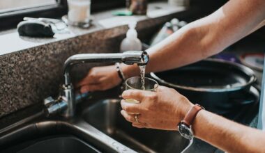 Person at a tap, filling a glass of water.