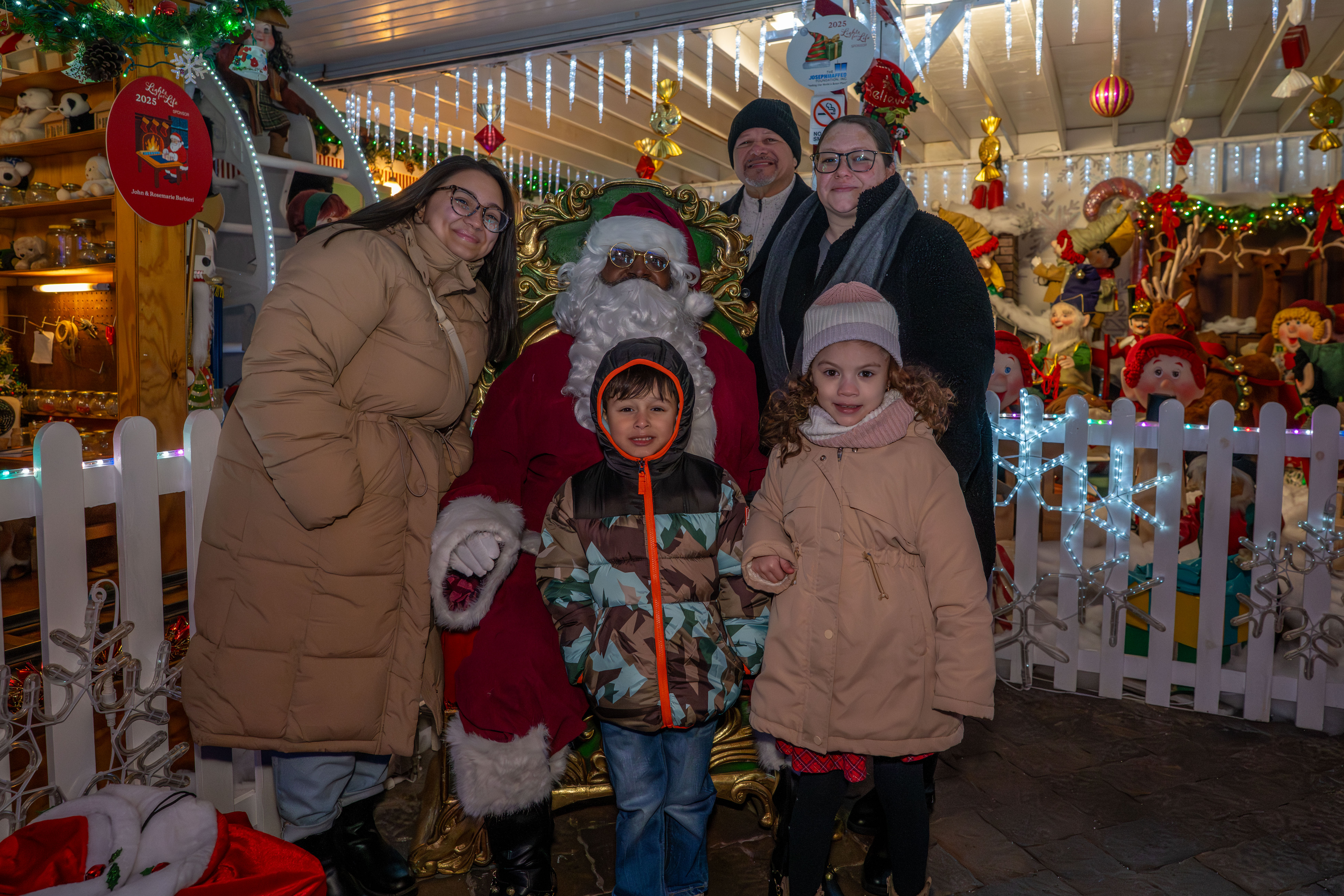 From the left, Tiffany Irizarry, Matthew Reyes, 4, Ralph Rivera, and Julissa Irizarry, 6, join Taisha Figueroa for a photo with Santa Claus at the DeMartino Christmas House in Charleston on Tuesday, December 16, 2025. Figueroa is a Northwell Staten Island University Hospital employee who is being honored with a Day of Surprises. (Owen Reiter for the Advance/SILive.com)