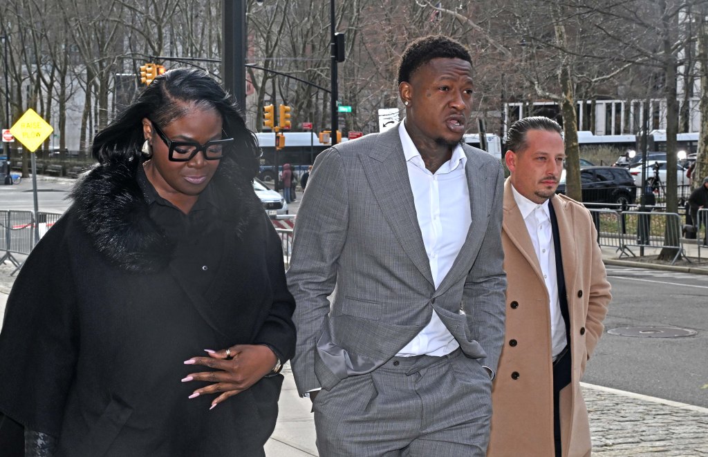 NBA player Terry Rozier (center, gray suit) arrives at court for an arraignment with two people.
