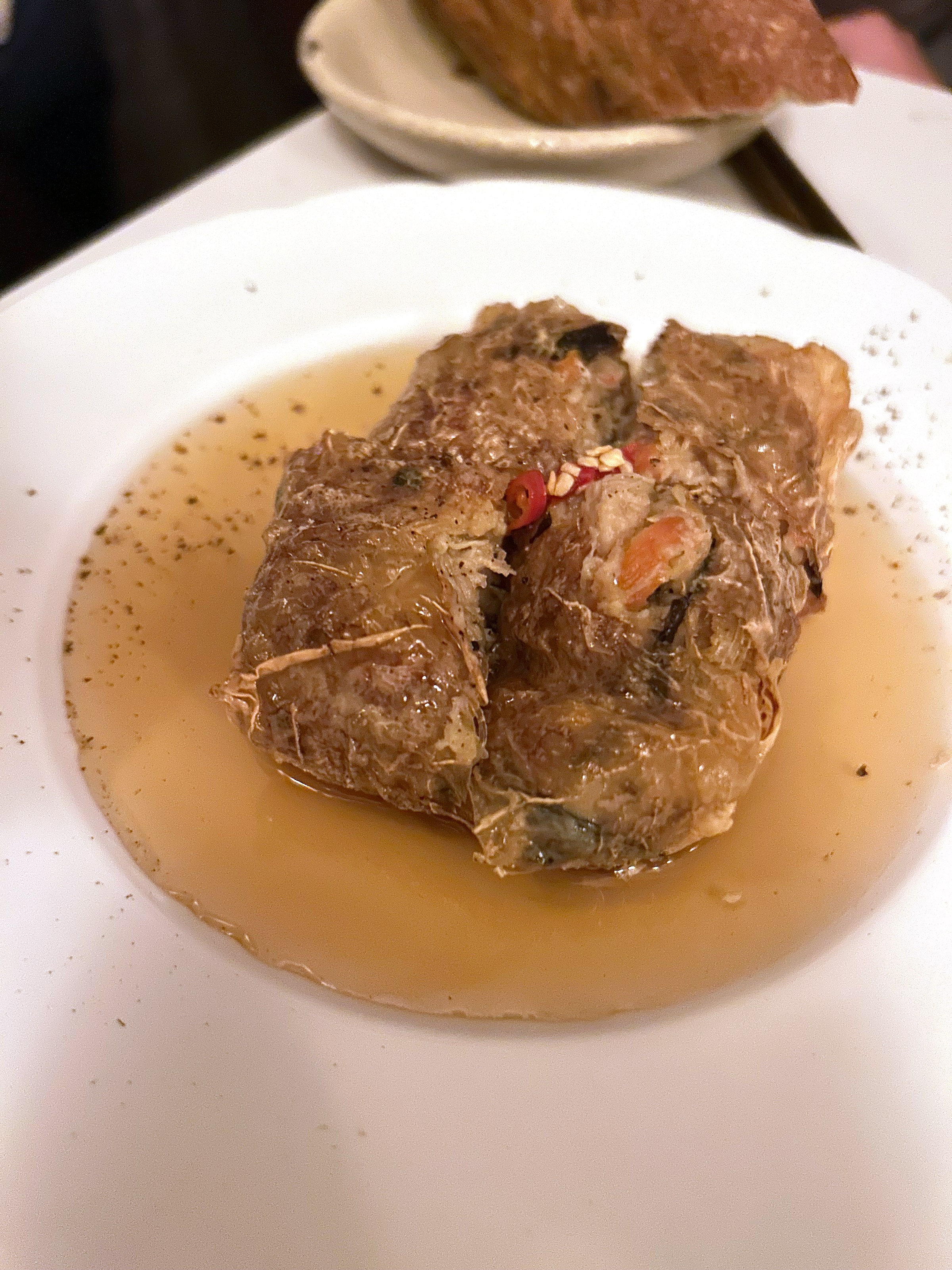 A fried tofu dish in a plate of beige broth.
