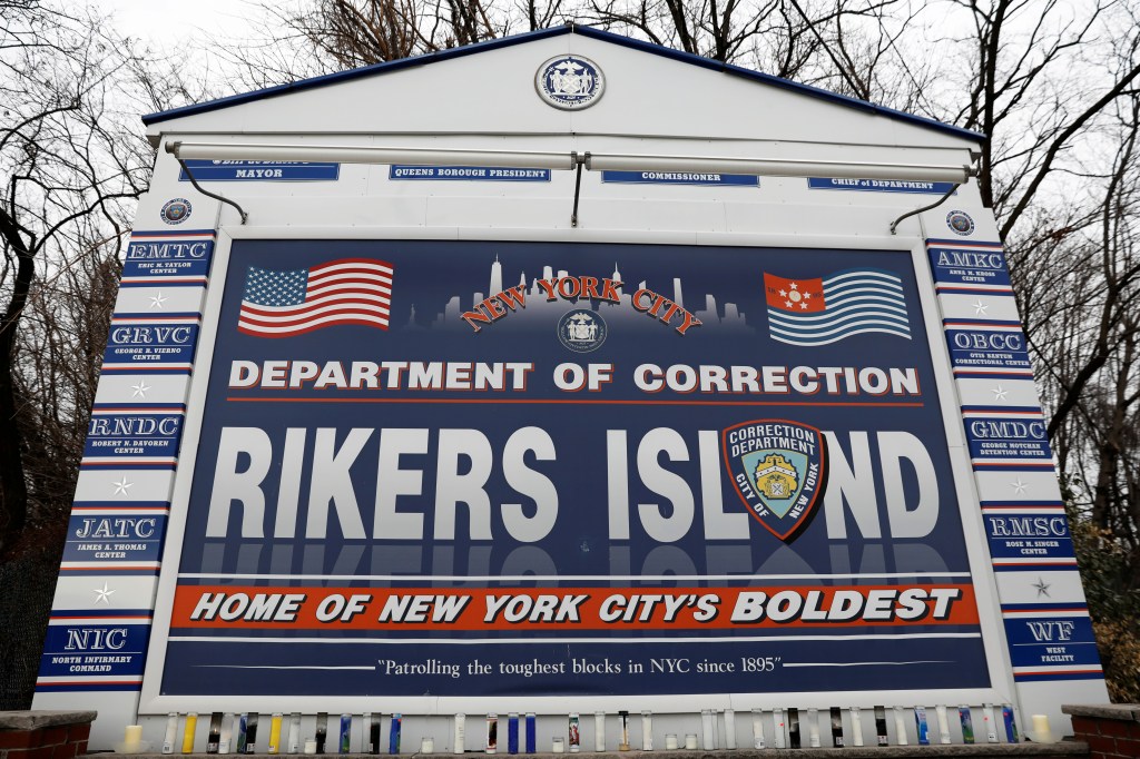 Candles at the entrance sign for Rikers Island correctional facility.