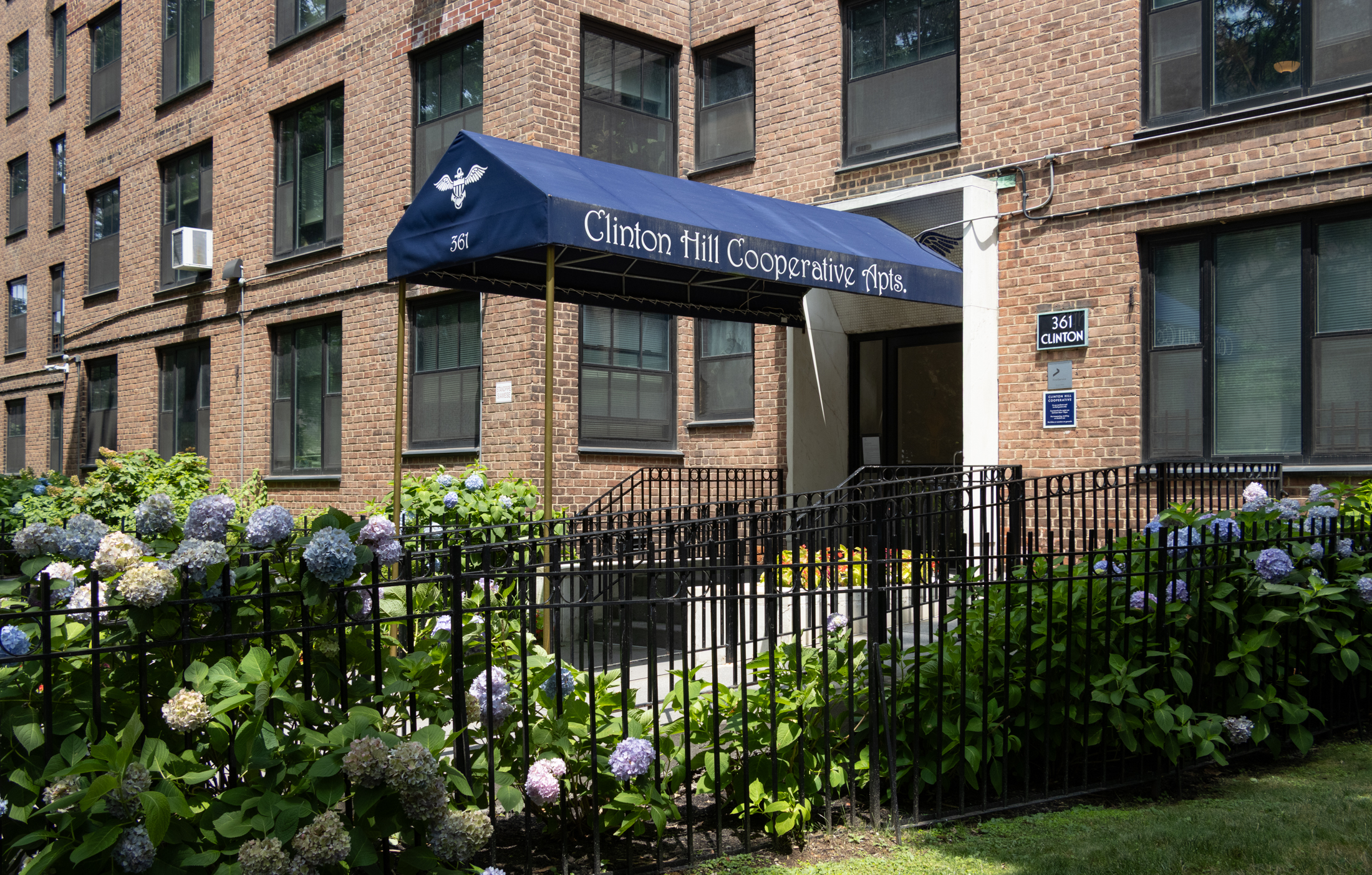 a blue awning over a door with the words clinton hill cooperatives