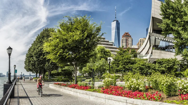 Battery Park City, people and a bicycle along the Esplanade. On the background the One World Trade Center skyscraper (also known as Freedom Tower, designed by the architect David Childs)