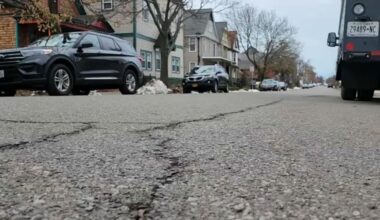A street with cars and houses in the background