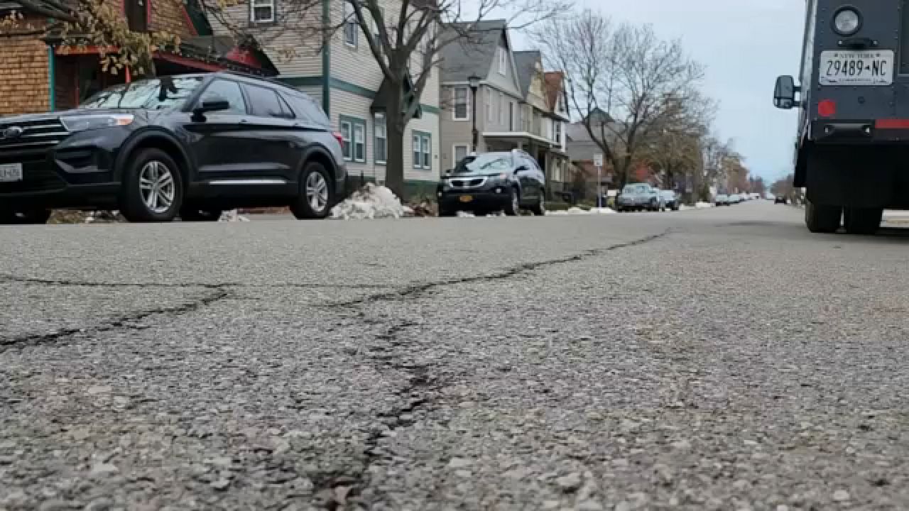 A street with cars and houses in the background