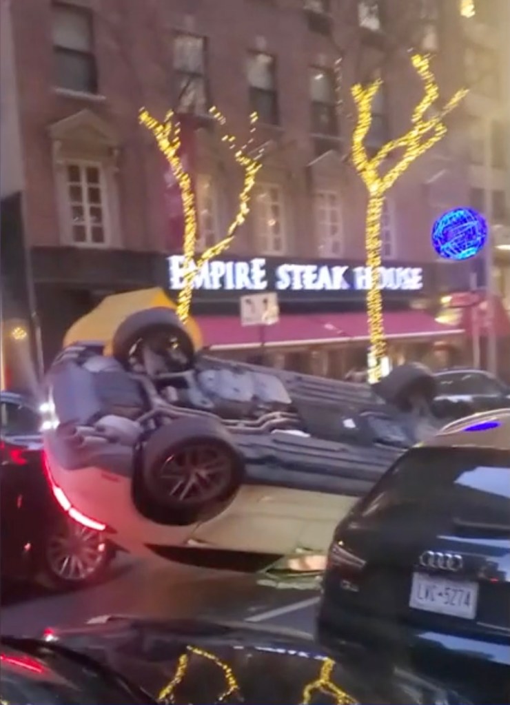 An overturned white Porsche on a city street in front of "Empire Steak House."