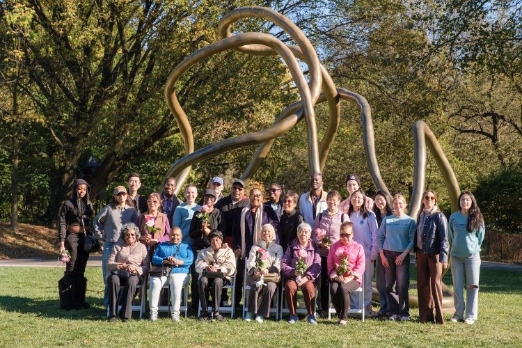 One of the Life Story Club groups sits together, smiling at the camera, in a park. 