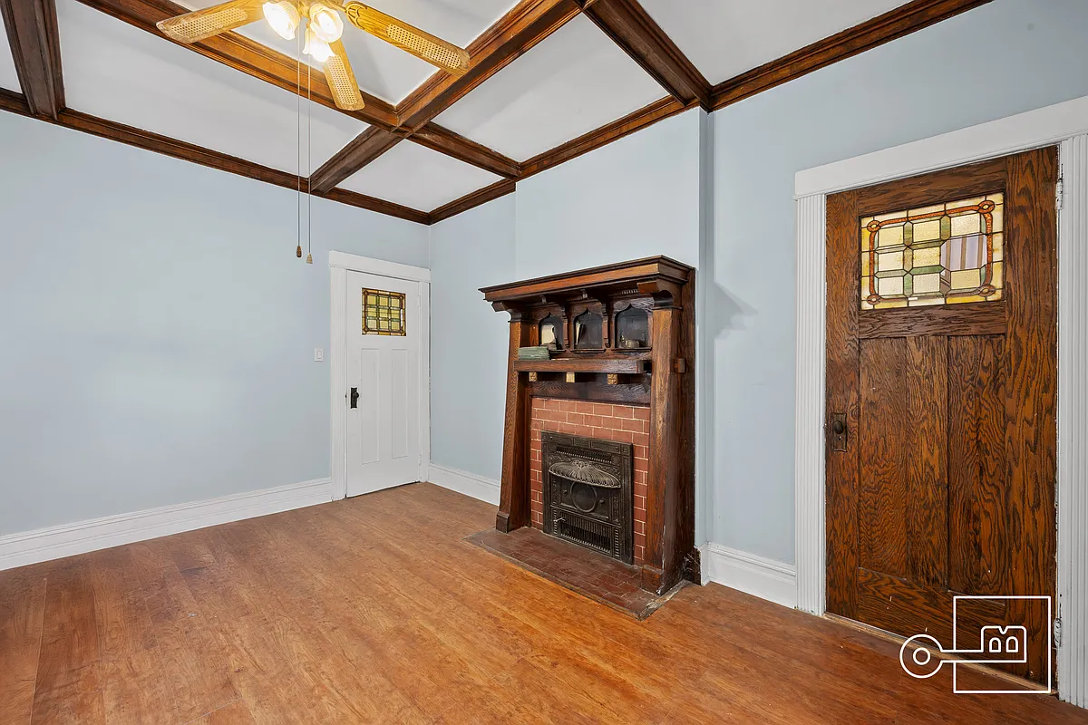 parlor with arts and crafts mantel, stained glass windows in doors and a beamed ceiling