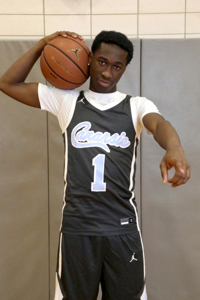 Nana Donkor posing with a basketball on his shoulder, wearing a black basketball jersey with "Canarsie" and number "1" in light blue.