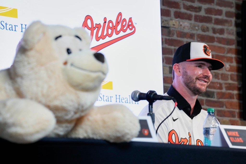 Pete Alonso smiles while wearing a Baltimore Orioles hat and jersey at a press conference.