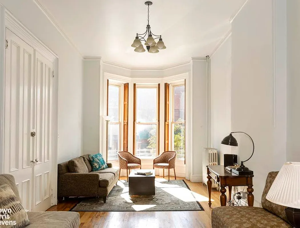 parlor with shutters in bay window, wood floor, white walls