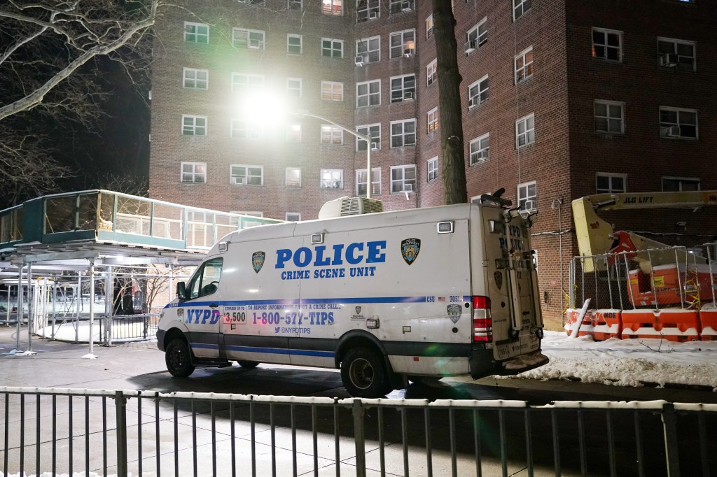 A white NYPD Crime Scene Unit van parked on a snowy street at night, with a brick apartment building in the background.