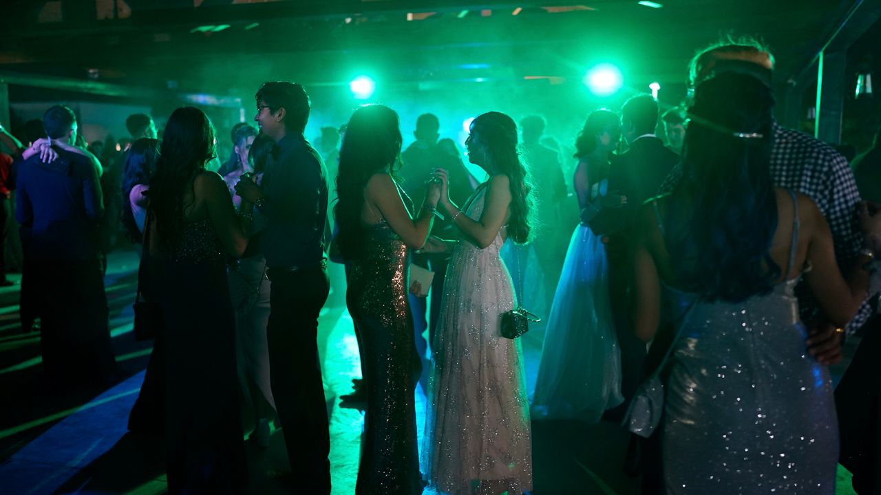 awkward promgoers under green lights on the dance floor