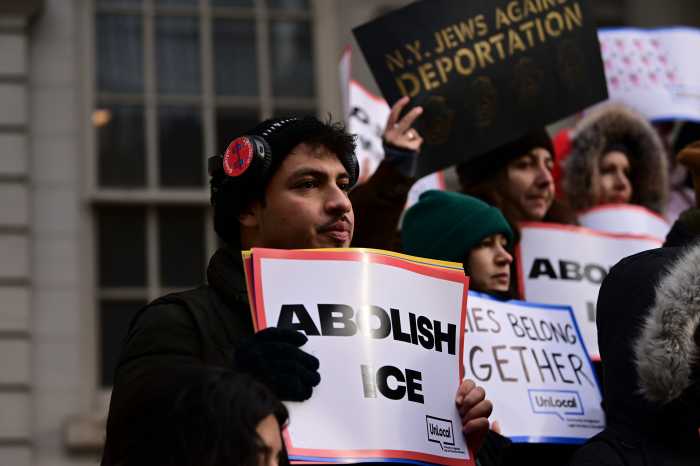 man holding a large sign and wearing a black coat