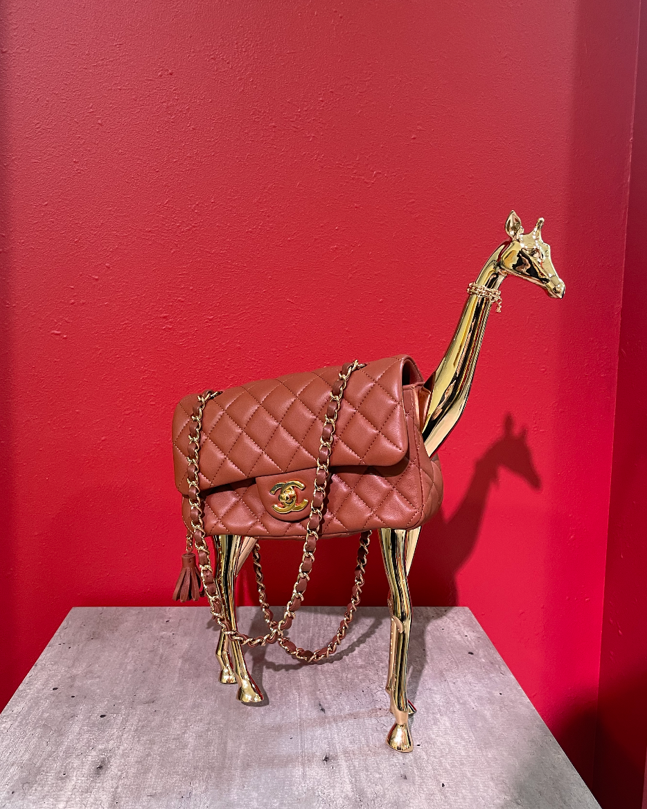 decorative giraffe sculpture holding a handbag