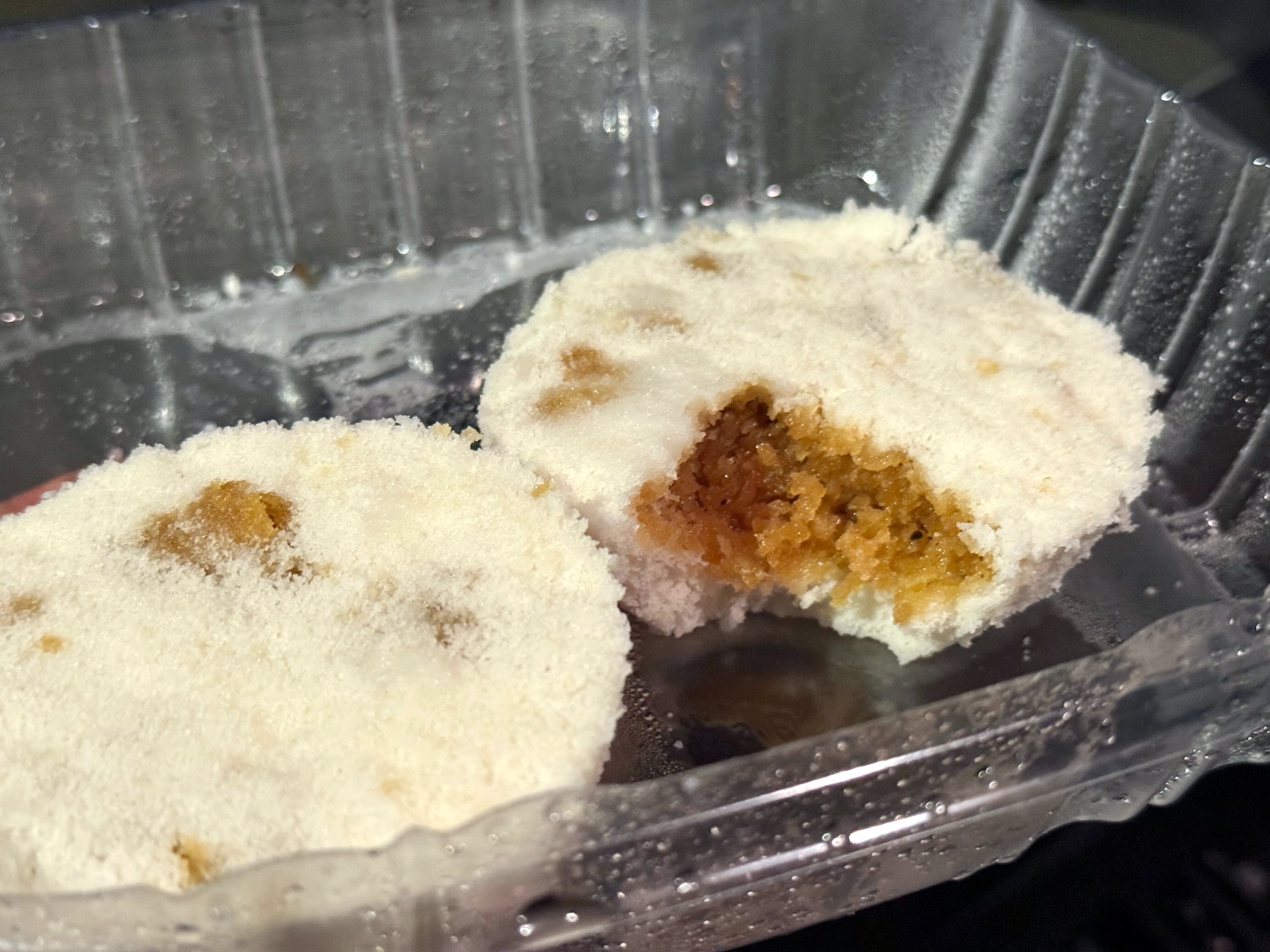 Two fried white cakes with one broken into with brown filling.