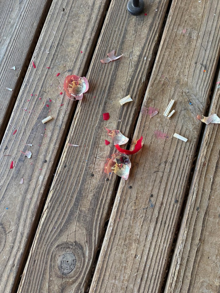 Shattered pink ornament and paper notes from a time capsule on wooden planks.