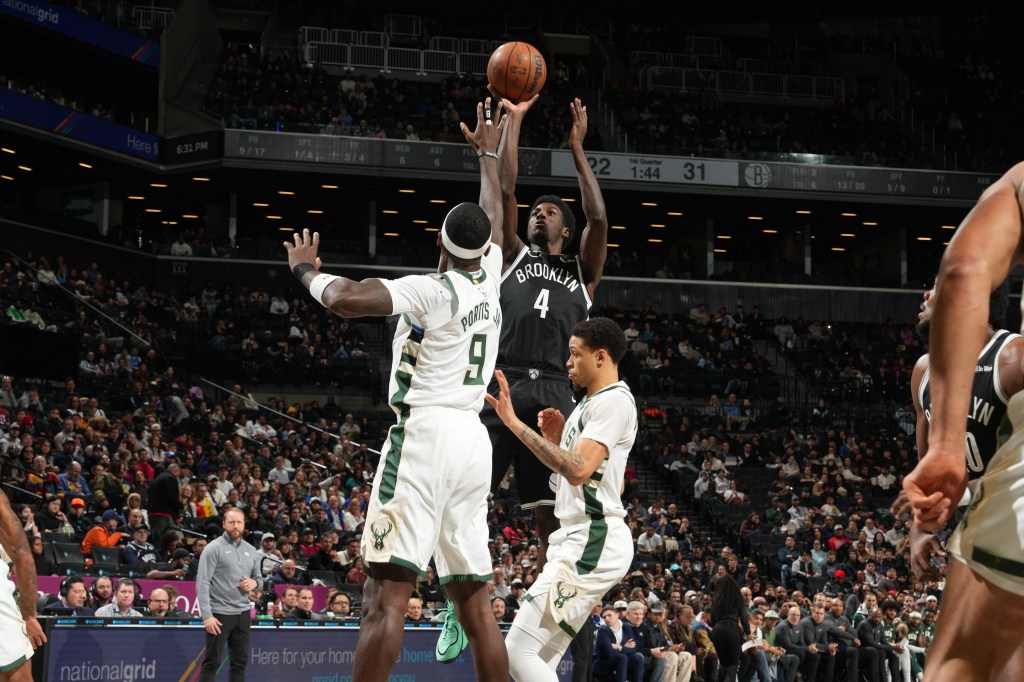 Drake Powell #4 of the Brooklyn Nets shoots the ball while being defended by Bobby Portis Jr. #9 and another player from the Milwaukee Bucks.