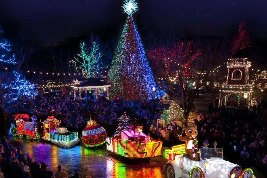 Christmas parade in Branson, Missouri, with floats on a street lined with spectators and a large illuminated Christmas tree.