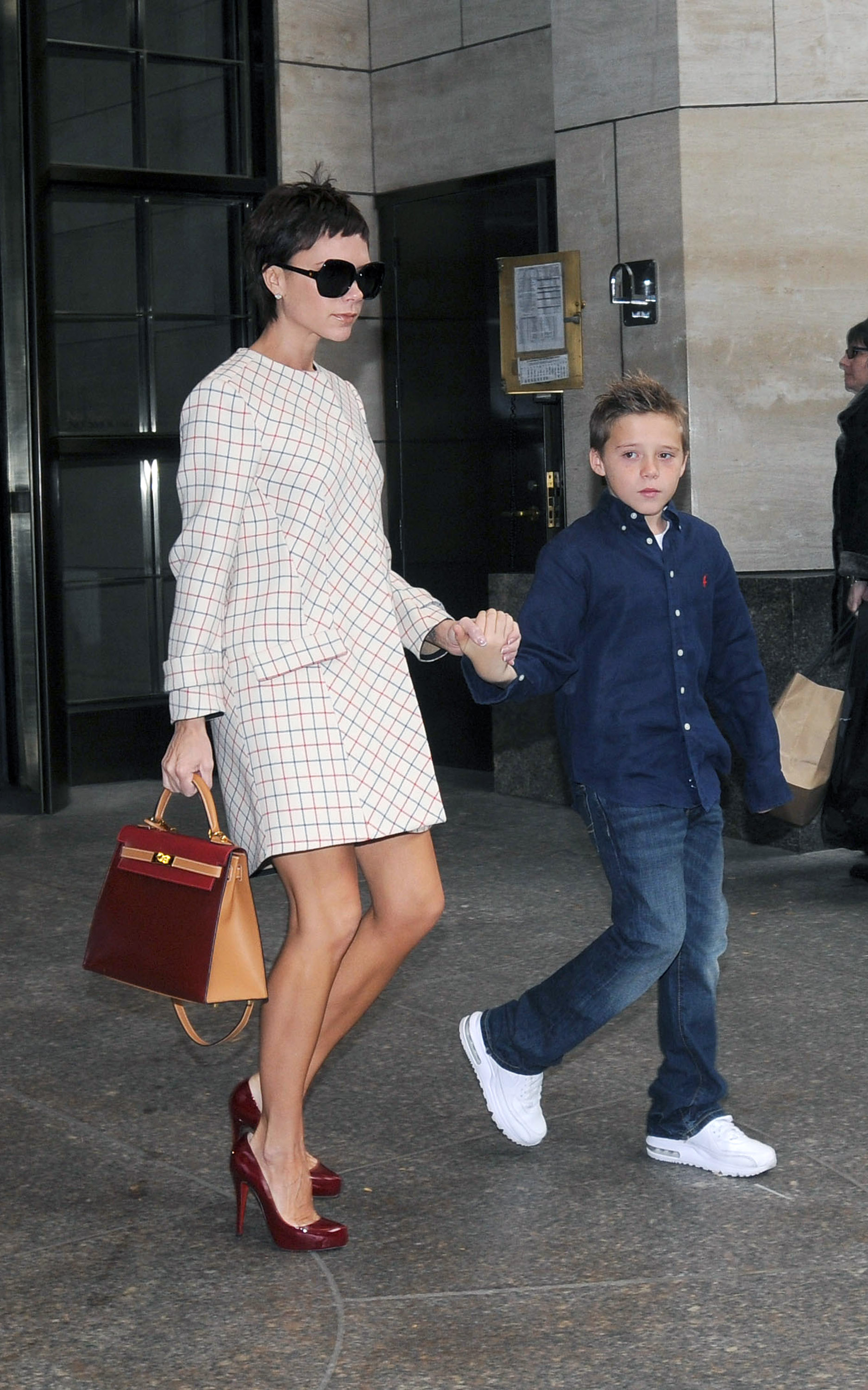 Victoria Beckham holds hands with her son Brooklyn Beckham in front of the Plaza Hotel.