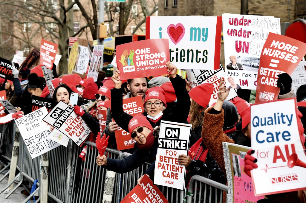 A crowd of nurses holding signs advocating for better patient care and staffing.