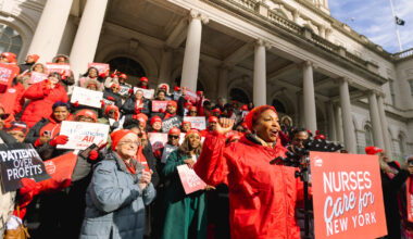 Nurses outside building behind podium with sign "Nurses Care for New York"