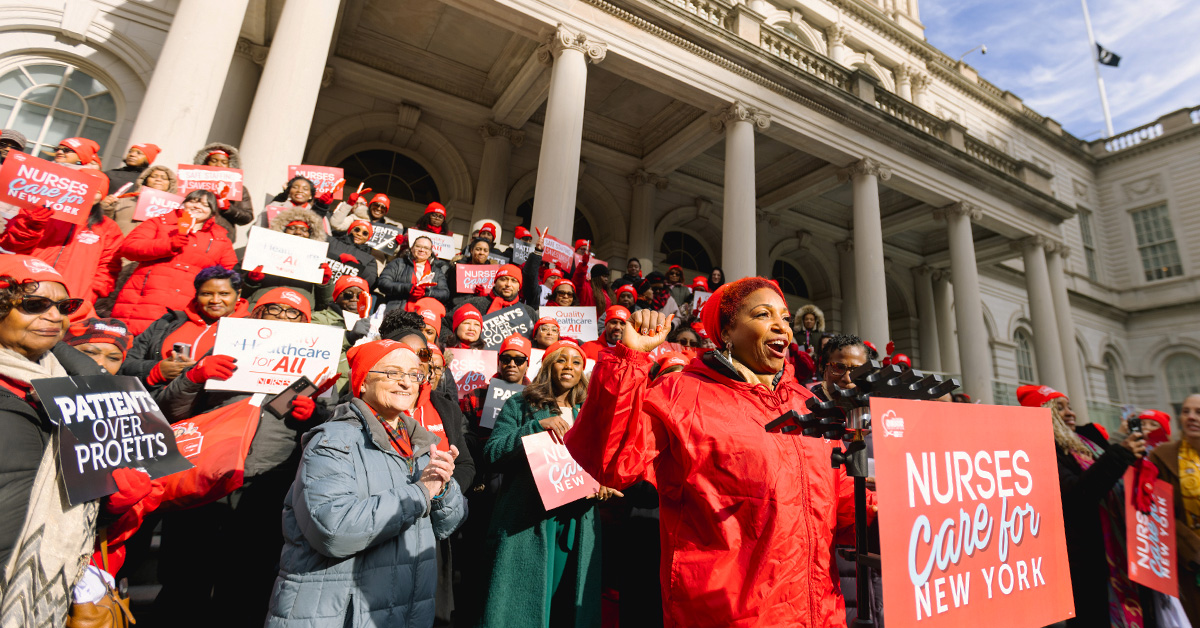 Nurses outside building behind podium with sign "Nurses Care for New York"