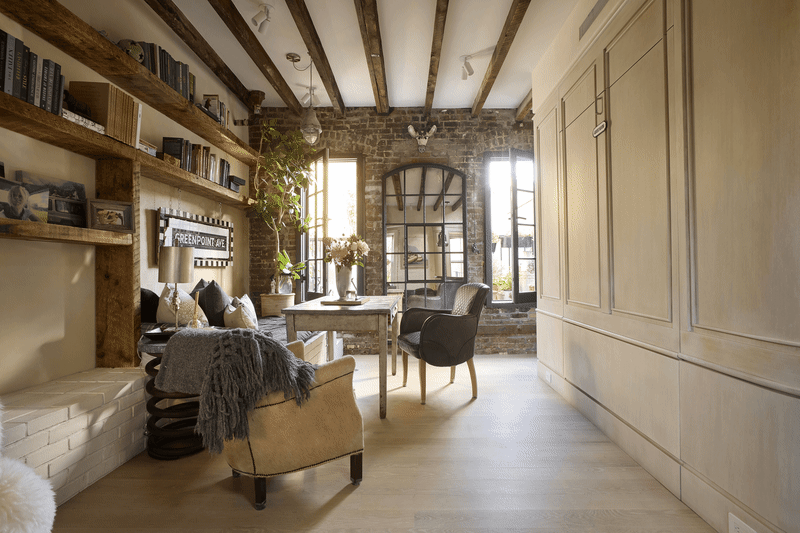 Cozy living space with exposed brick walls, wooden beams, a rustic table, and a comfortable chair.