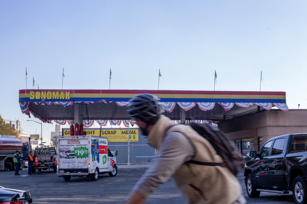 A person rides a bike past a Sonomax gas station in Greenpoint
