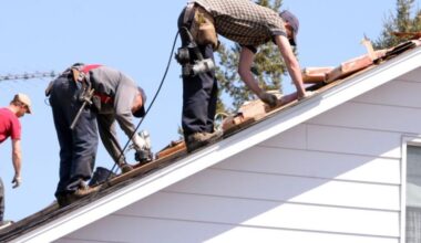 Workers installing roofing tiles on a pitched roof.