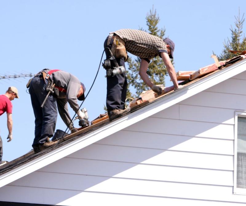 Workers installing roofing tiles on a pitched roof.