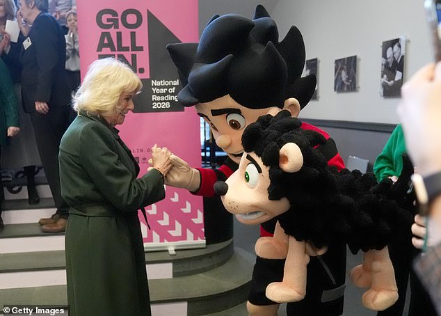 Queen Camilla greets some cartoon characters as she visits the library today