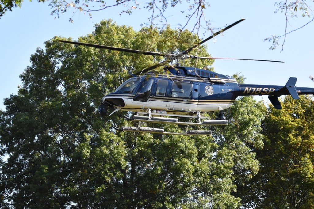 New York State Police helicopter hovering above trees.