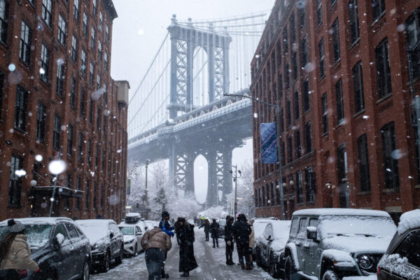 People gather on Washington Street in front of Manhattan Bridge during a snowfall, Sunday, Dec. 14, 2025, in DUMBO. Photo: Adam Gray/AP