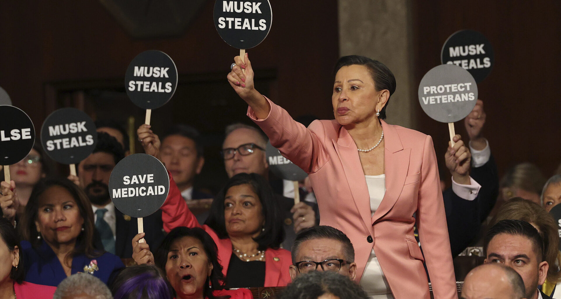 Rep. Nydia Velazquez, D-N.Y., holds a protest sign with fellow Democrats as President Donald Trump addresses a joint session of Congress at the Capitol in Washington, Tuesday, March 4, 2025.