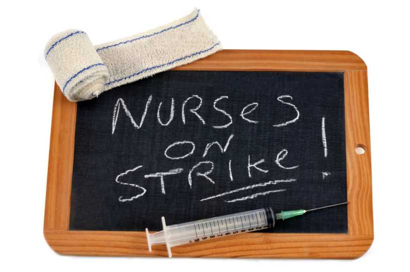 Bandage and syringe with a school slate on which is written in English nurses on strike
