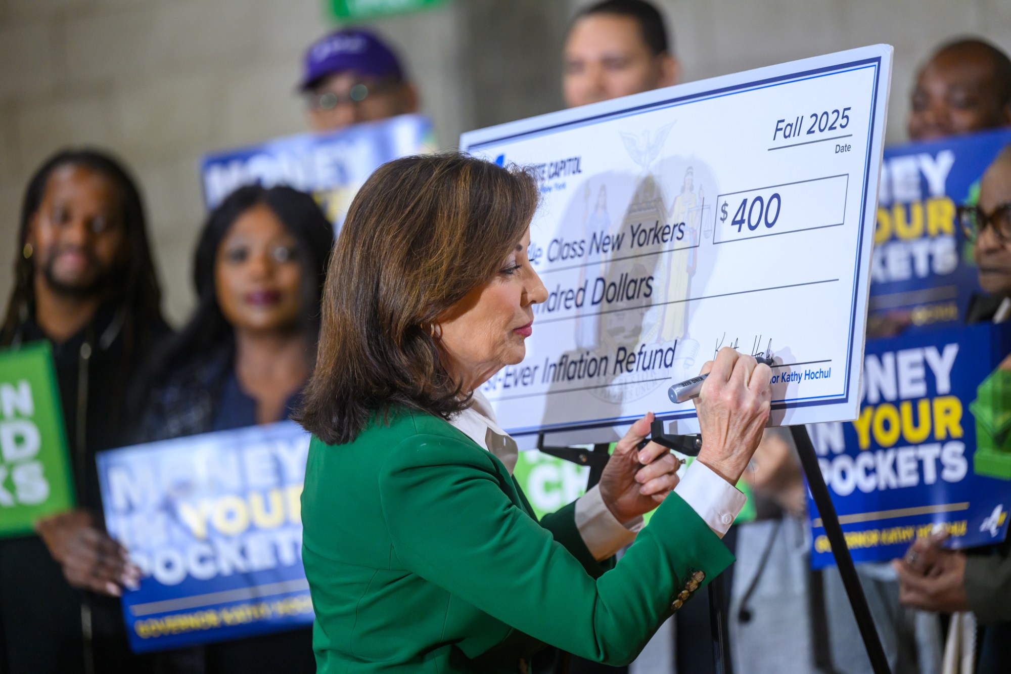 Gov. Kathy Hochul signs a display inflation refund check,
