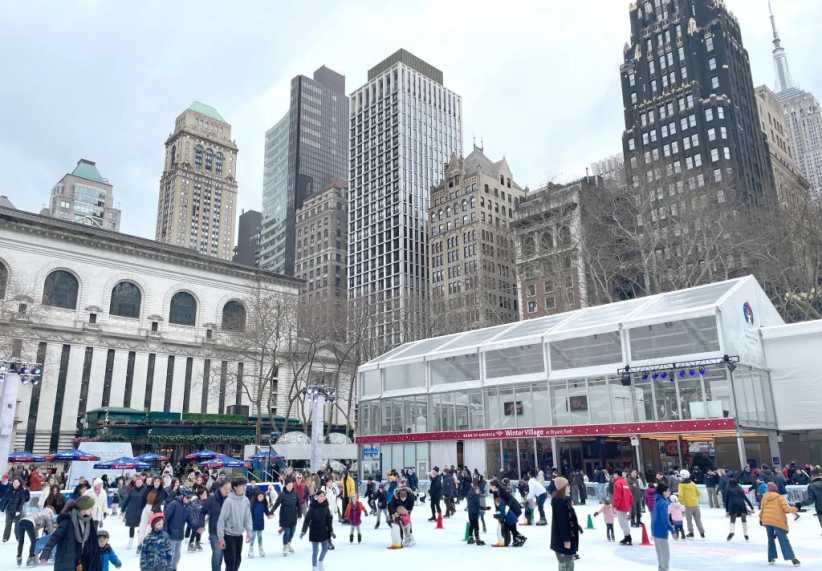 Crowded ice rink filled with people having winter fun at Bryant Park's ice skating rink