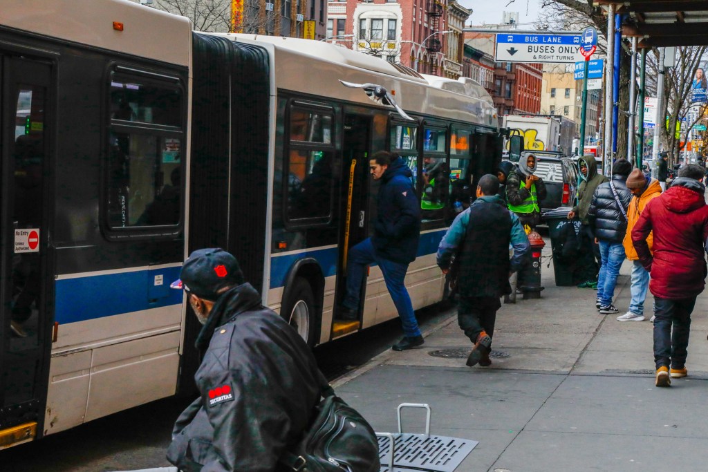 Commuters board an MTA bus on East 125th Street,