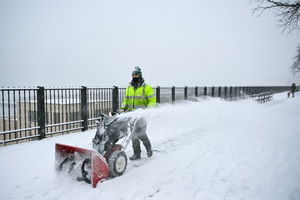 A worker clears snow from the Brooklyn Heights Promenade in New York City on January 25, 2026. A massive winter storm on January 24 dumped snow and freezing rain from New Mexico to North Carolina as it swept across the United States towards the northeast, threatening tens of millions of Americans with blackouts, transportation chaos and bone-chilling cold. After battering the country's southwest and central areas, the storm system began to hit the heavily populated mid-Atlantic and northeastern states as a frigid air mass settled in across the nation. (Photo by ANGELA WEISS / AFP via Getty Images)