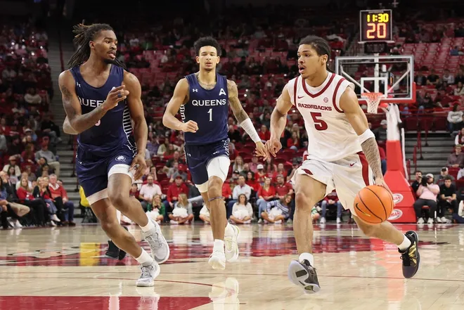 Dec 16, 2025; Fayetteville, Arkansas, USA; Arkansas Razorbacks guard Darius Acuff Jr (5) drives against Queens Royals forward vantage Parker (6) and guard Nasir Mann (1) defend during the second half at Bud Walton Arena. Arkansas won 108-80.