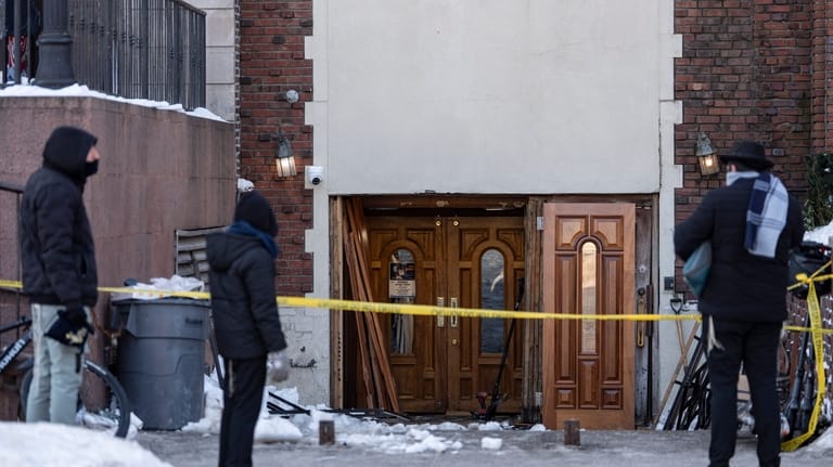 People watch the scene where a car slammed into the...