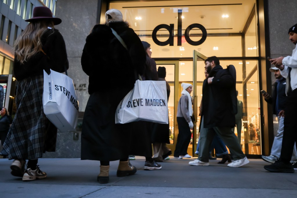 Pedestrians, including holiday shoppers carrying Steve Madden bags, walk past an Alo store on Fifth Avenue in New York City.